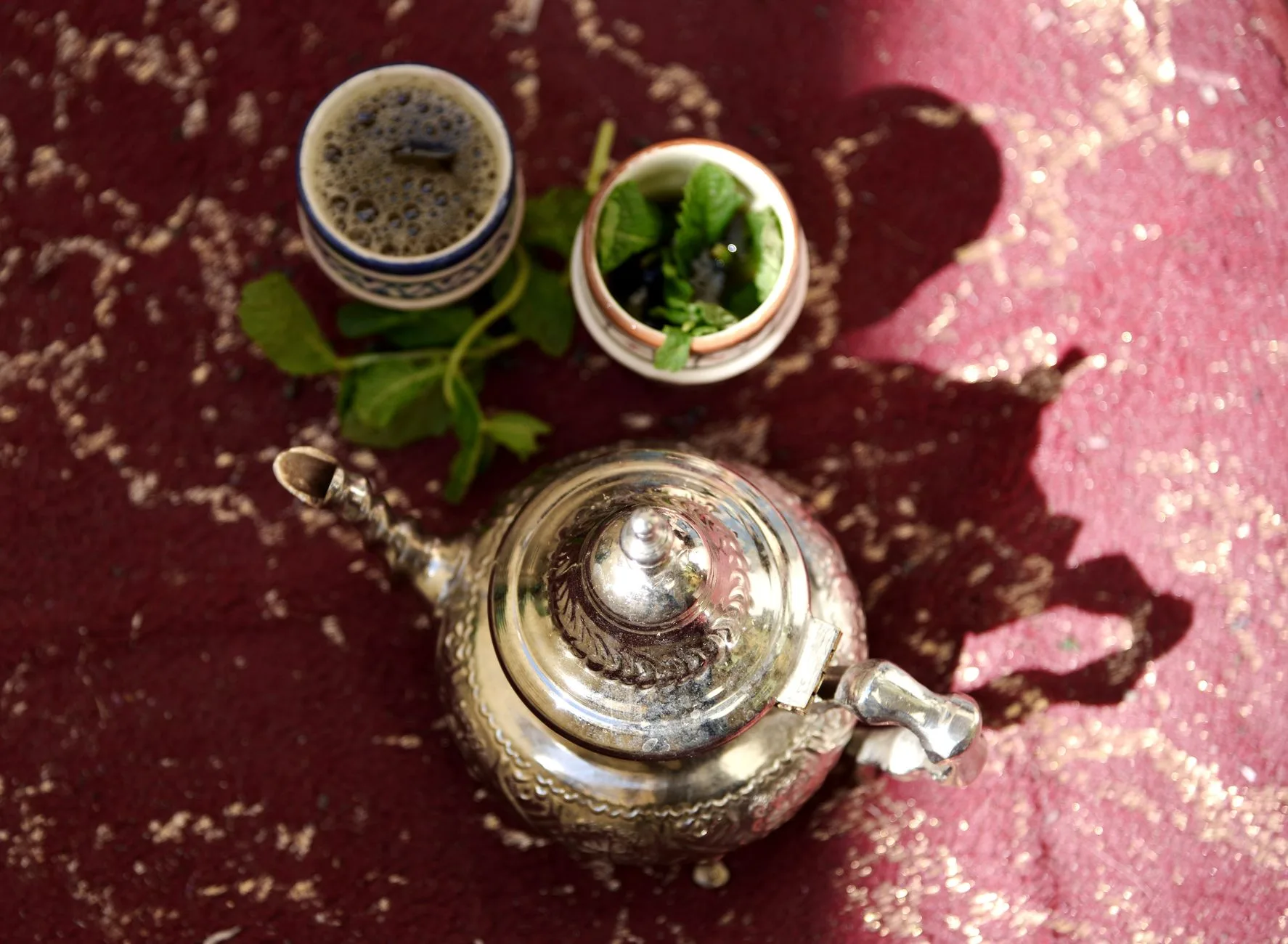 Service à thé à la menthe traditionnel marocain sur un tapis